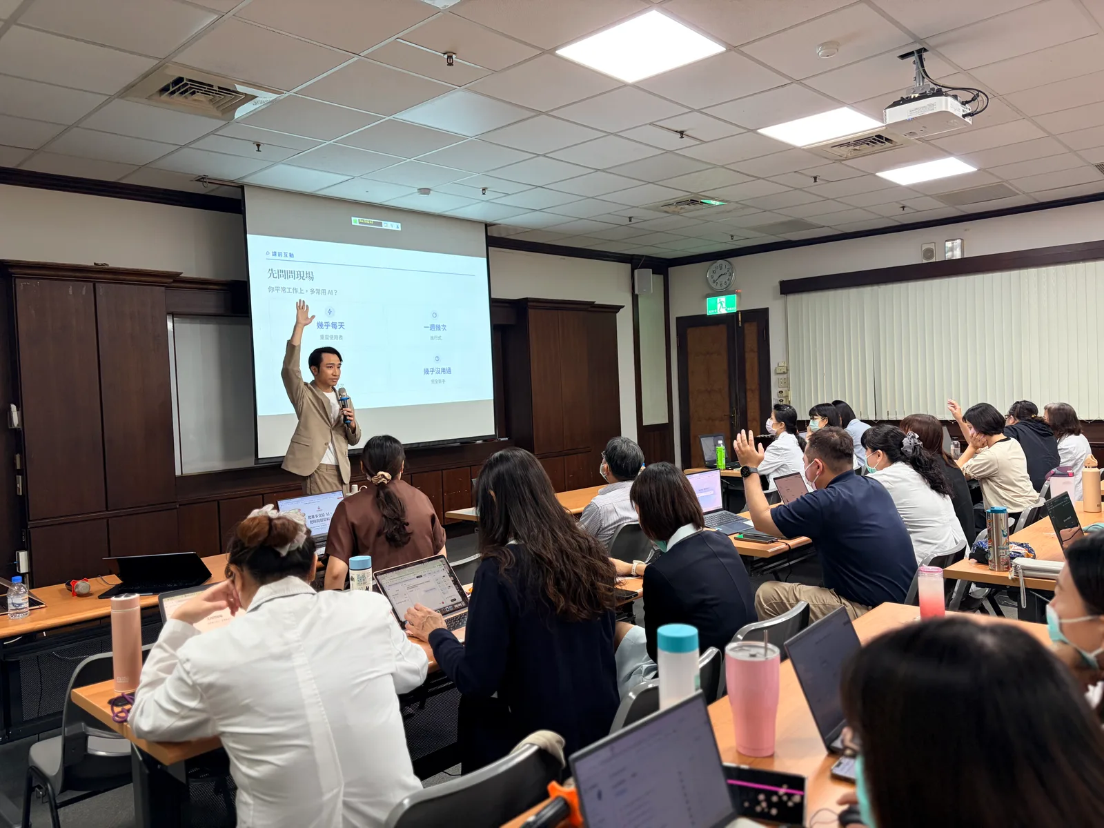 臺南新樓醫院教室內，多位醫事人員在筆電前舉手回應現場調查